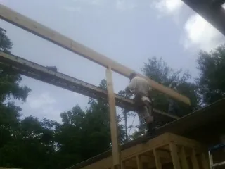 Carpenter setting a ridge beam over a new addition frame — Ice Dam Removal by Roofing Brothers in Dearborn