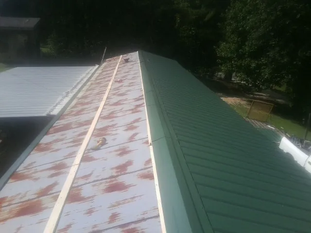 Old rusted panels beside newly installed green metal roofing — Wind Damage Roof Repair by Roofing Brothers in Dearborn
