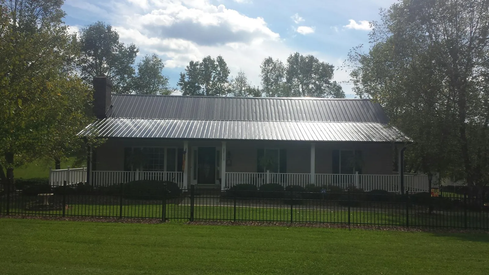 Gray metal roof on a brick ranch with a full width front porch — Gutter Guard Installation work by our crew in Dearborn